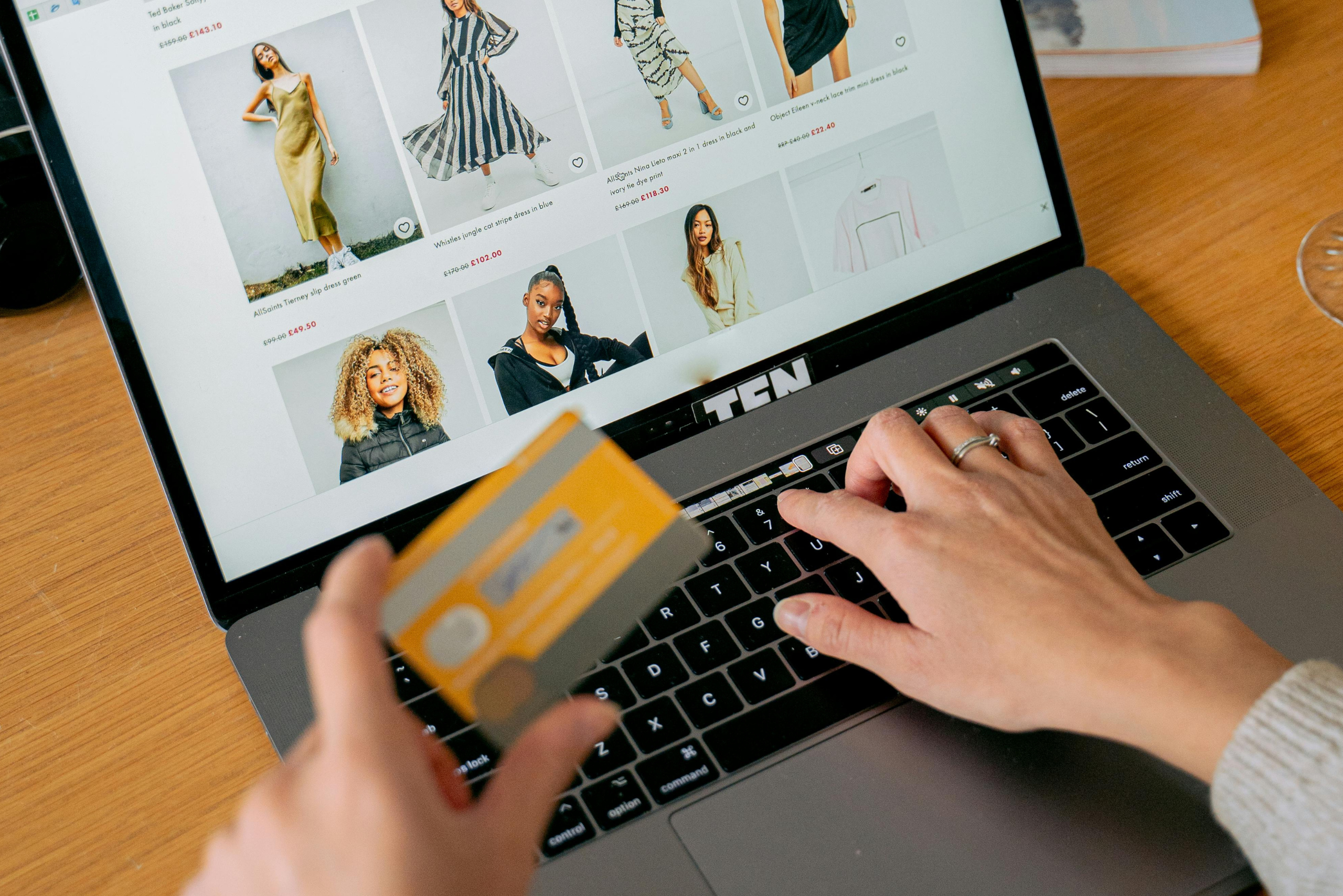 Pessoa realizando compra online com cartão de crédito em notebook representando problemas em compras digitais e relações de consumo na internet.